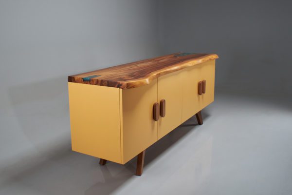 Image of a buffet named Belize, designed and constructed by Rangahaus. The buffet is made of solid natural elm wood with a green-blue pearl epoxy resin (liquid glass) finish, and measures L 200 cm x W 50 cm x H 80 cm. The lacquered box features drawers and cabinets for ample storage, and the base and handles are made of solid elm wood. The combination of natural wood and the unique green-blue pearl epoxy resin finish creates a striking and modern design, making it a perfect addition to any dining or living room. Diagonal view.