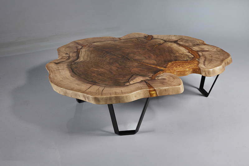 Image of a coffee table made of natural solid walnut wood impregnated in gold epoxy resin, supported by three legs in a black matte finish. The table features a smooth and glossy surface that highlights the natural beauty of the wood grain, and the gold epoxy resin provides a unique and eye-catching accent. The three legs in a black matte finish add a modern and sophisticated touch to the overall design. High angle view.