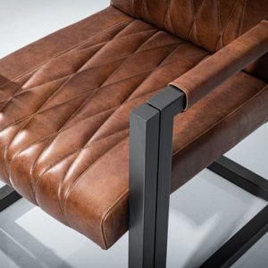 Close-up view of a metal dining armchair. Powder-coated metal frame in geometrical shape and dark gray matte finish. Seat and backrest upholstered in real brown leather with diamond-shape pattern.