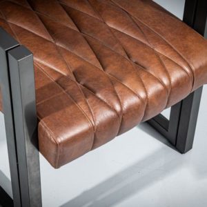 Close-up view of a metal dining armchair. Powder-coated metal frame in geometrical shape and dark gray matte finish. Seat and backrest upholstered in real brown leather with diamond-shape pattern.
