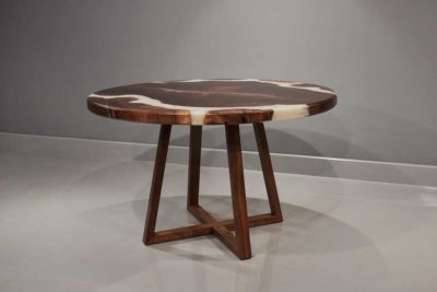 Image of a one-of-a-kind White Pearl round table with natural solid walnut wood root and white pearl epoxy resin in a matte finish, resting on a criss cross solid walnut wood base. High angled view.