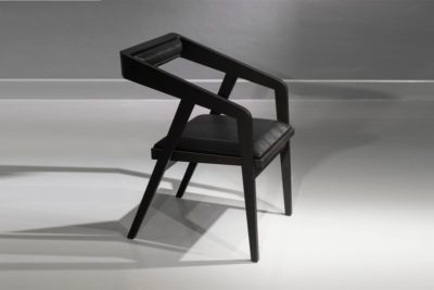 High Angle view of a black wooden dining chair with arms. Upholstered in black leatherette. Total black dining chair.